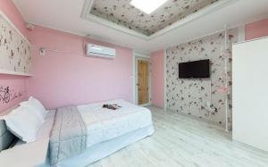 a pink bedroom with a bed and a flat screen tv at Sunbeach Pension in Geoje 