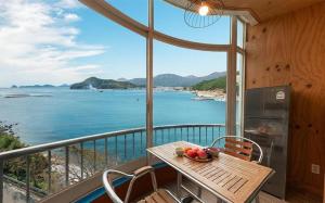 a table and chairs on a balcony with a view of the water at Sunbeach Pension in Geoje 
