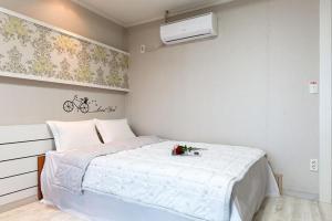 a bedroom with a large white bed with flowers on it at Sunbeach Pension in Geoje 