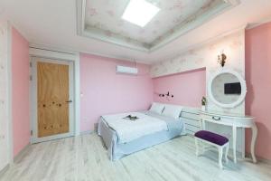 a pink bedroom with a bed and a table and a mirror at Sunbeach Pension in Geoje 
