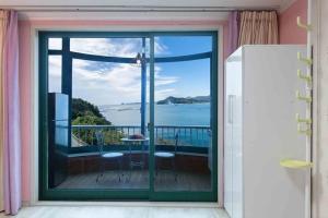 a room with a balcony with a view of the ocean at Sunbeach Pension in Geoje 