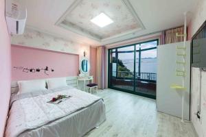 a bedroom with a large bed with a pink wall at Sunbeach Pension in Geoje 
