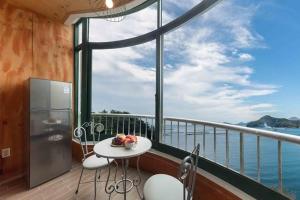 a balcony with a table and chairs and a large window at Sunbeach Pension in Geoje 