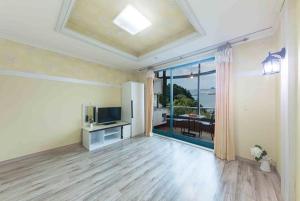 an empty living room with a television and a large window at Sunbeach Pension in Geoje 