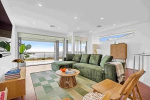 a living room with a green couch and a table at 180 View by Wine Coast Holiday Rentals in Aldinga Beach