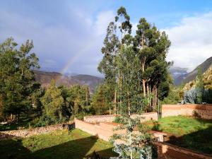 un arcobaleno tra le montagne con un muro e alberi di Cozy mountain house a Urubamba