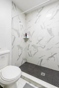 een badkamer met een wit toilet en zwarte en witte tegels bij Gorgeous Manhatten Gem in New York