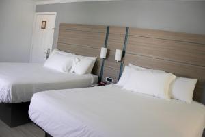 2 letti in camera d'albergo con cuscini bianchi di Discovery Inn a Hayward