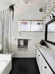 La salle de bains blanche est pourvue d'une baignoire et d'un lavabo. dans l'établissement Rare Find! 5-Bedroom Home with Pool and Pool Table, à Muswellbrook