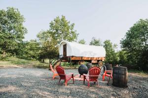 a group of chairs and a trailer with a tent at Heated & AC Full Bathroom Covered Wagon in Penn Yan