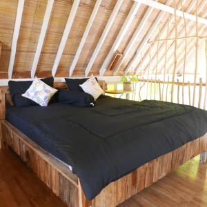 Una cama con edredón negro y almohadas. en Pondok isoke en Banyuwangi