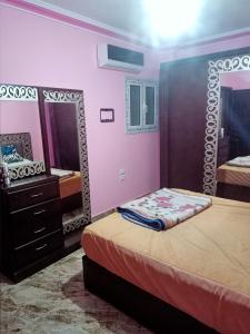 um quarto com 2 camas e uma cómoda e espelhos em شقه مفروشه مكيفه نضيفه للايجار علي جسر السويس no Cairo