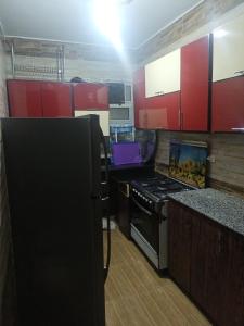 uma cozinha com armários vermelhos e um forno com placa de fogão em شقه مفروشه مكيفه نضيفه للايجار علي جسر السويس no Cairo