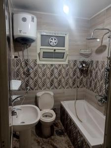 uma casa de banho com um WC, uma banheira e um lavatório. em شقه مفروشه مكيفه نضيفه للايجار علي جسر السويس no Cairo