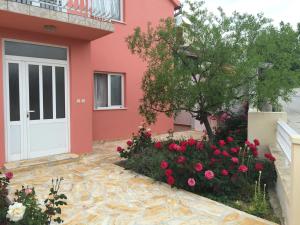 una casa rosa con una puerta blanca y flores en Apartments Bibic, en Vodice