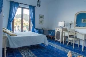 a bedroom with a bed and a desk and a window at Hotel Rocce Azzurre in Lipari