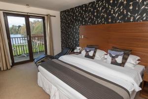 a bedroom with a large bed and a balcony at The Lodge on the Loch in Aboyne