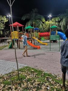 un niño pequeño jugando en un patio de juegos por la noche en Casa Piratininga Niterói Rj, en Niterói