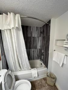 a bathroom with a toilet and a tub with a shower curtain at Thriftlodge Saskatoon in Saskatoon