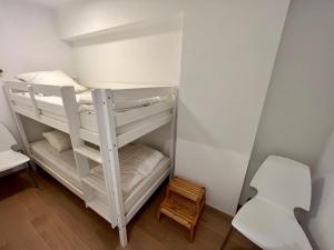 Zeedijk family apartment في كنوك هايست: سرير بطابقين أبيض في غرفة صغيرة مع كرسي