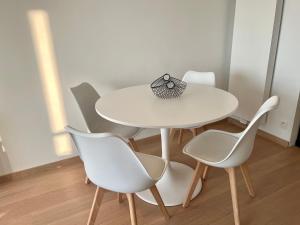 een witte tafel en stoelen in een kamer bij Zeedijk family apartment in Knokke-Heist