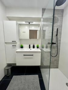 y baño blanco con lavabo y ducha. en Zeedijk family apartment en Knokke-Heist