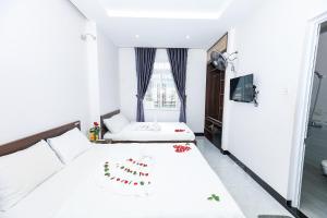a white bedroom with two beds and a window at Ciao Hồng Phúc Hotel in Quy Nhon