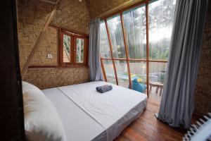 a bed in a room with a large window at La Vie en Rose in Senggigi 