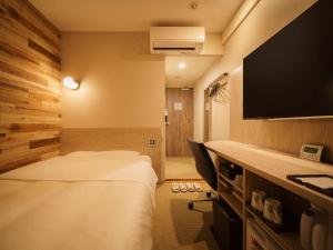 a hotel room with two beds and a flat screen tv at Super Hotel Shinbashi-Karasumoriguchi in Tokyo
