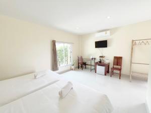 a white bedroom with a bed and a desk and a television at On Green Resort in Ban Huai Sua