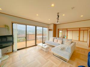 a living room with a couch and a tv at Izu Serenity Fuji-View Retreat with Private Onsen in Izu