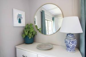 un espejo sentado en la parte superior de un tocador con una lámpara en Banksia Cottage, pretty cottage with garden, en Leura
