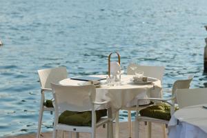 une table et des chaises blanches à côté de l'eau dans l'établissement Vila Perast Boutique Hotel, à Perast