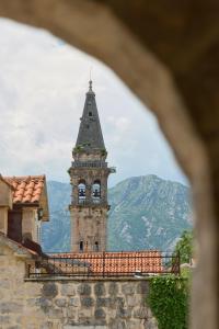 una torre alta con un reloj en la parte superior de un edificio en Vila Perast Boutique Hotel en Perast