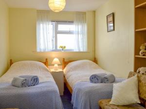 two twin beds in a room with a window at Rivendell in Blakeney