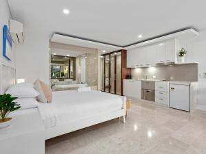 a white bedroom with a large bed and a kitchen at Santai Resort - Holiday Management in Kingscliff