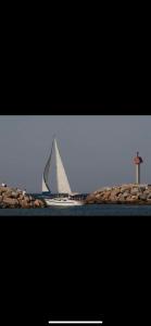 a sail boat in the water with a lighthouse at Camping 4 étoiles Le Bosc Saint Cyrpien Mobil Home in Saint-Cyprien