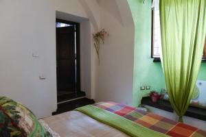 Schlafzimmer mit einem Bett und einem Fenster mit grünen Vorhängen in der Unterkunft B&B Va...lentina in Piavata