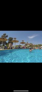 a swimming pool with umbrellas and people in the water at Camping 4 étoiles Le Bosc Saint Cyrpien Mobil Home in Saint-Cyprien