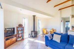 sala de estar con sofá azul y fogones en Berrara Lagoon Front Chalet, en Berrara