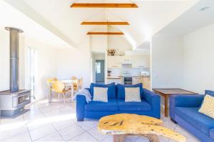 a living room with a blue couch and a stove at Berrara Lagoon Front Chalet in Berrara