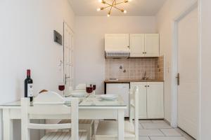 cocina blanca con mesa blanca y sillas en Golden Silence Studios, en Agios Prokopios