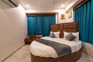 a bedroom with a large bed with blue curtains at Hotel Royal 24 in Ahmedabad