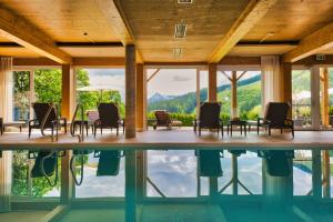 a pool with chairs and a view of the mountains at Landhaus Ramsau in Ramsau am Dachstein