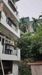 um edifício de apartamentos branco com varanda e árvores em HIDDEN GEM*HEART of THE OLD QUARTER*5BR*FULL HOUSE em Hanói