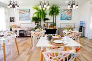 un restaurante con mesas blancas, sillas y plantas en Finca El Pastel en Tacoronte