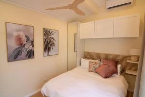 a bedroom with a white bed and some pictures on the wall at Bottlebrush Cabin, cosy private cabin in the trees in Leura