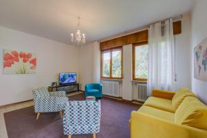 un soggiorno con divano giallo e sedie di The Bon'Ora Apartment - Happy Rentals a Riva del Garda