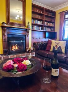 a living room with a fireplace and a table with a glass of wine at Mudgee Homestead Guesthouse in Mudgee