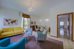 un soggiorno con divano giallo e sedie di The Bon'Ora Apartment - Happy Rentals a Riva del Garda